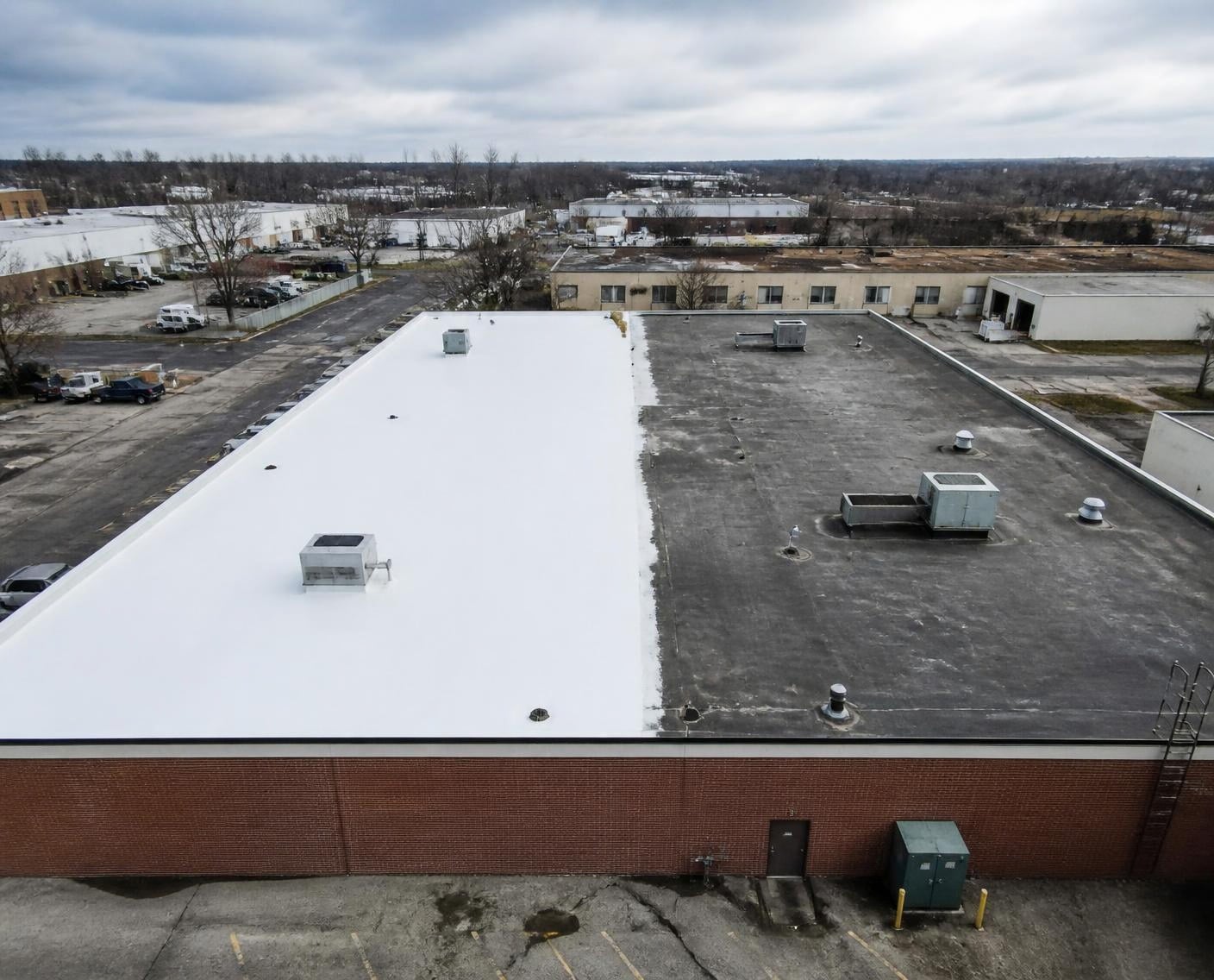 Aerial view of a flat commercial roof half coated in white
