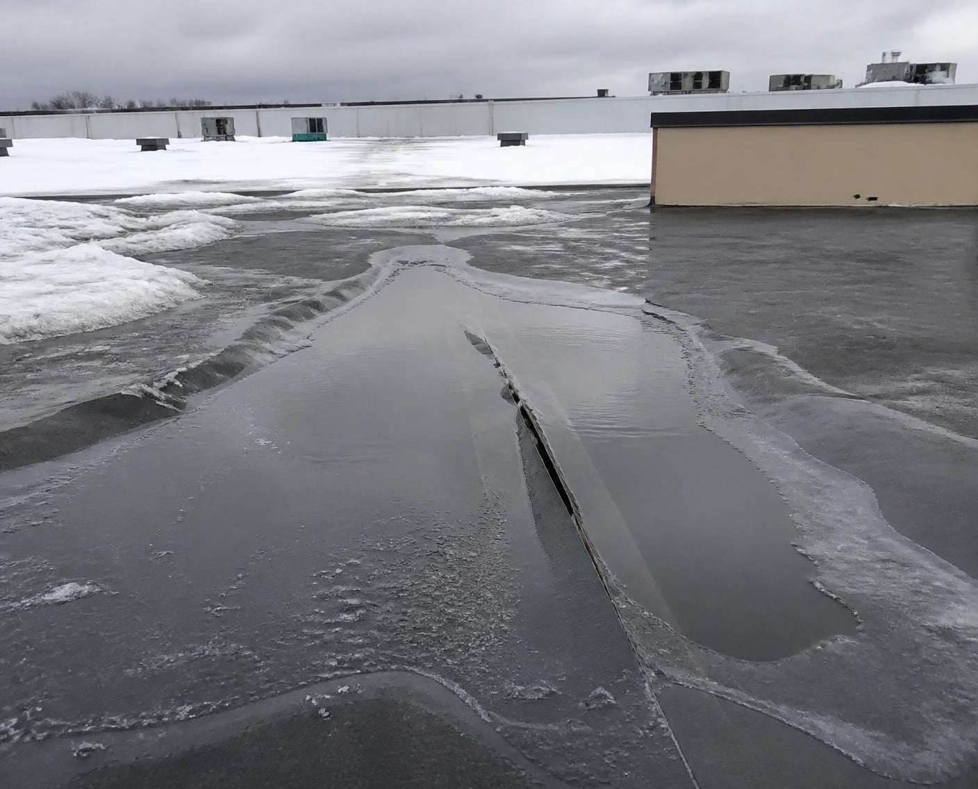 Snowmelt ponding against a lifting seam on a flat roof